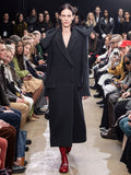 Model Walking in Proenza Schouler Fall Winter 2024 Runway Show Wearing Reed Coat in Charcoal Brushed Wool, Silo Bag in Black Nappa, and  Monogram Loafers in Rosewood Shiny Eel