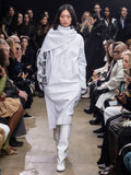 Model Walking in Proenza Schouler Fall Winter 2024 Runway Show Wearing Andy Dress in Cloud Nappa, Split Tote in Light Grey Nappa, and Tee Knee High Boots in White Nappa