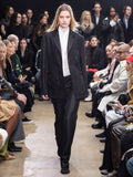 Model Walking in Proenza Schouler Fall Winter 2024 Runway Show Wearing Bronte Jacket in Black Double Weave Viscose Organza, Rio Top in Bone Tulle Jersey, Demi Shirt in Bone Silk Viscose, Chase Pant in Black Technical Mesh Suiting, and Tee Over the Knee Boots in Black Viscose Knit With White Ties