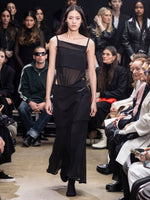 Model Walking in Proenza Schouler Fall Winter 2024 Runway Show Wearing Dani Dress in Black Crepe Chiffon / Wool Gabardine and Tee Over the Knee Boots in Black Viscose Knit