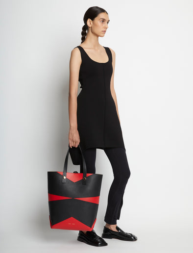 Image of model carrying Pieced North South Tobo Tote in bright red/black