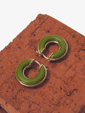 Image of mini hoop earrings in olive against brick