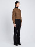 Side full length image of model wearing Chunky Cable Bell Sleeve Sweater in DARK CAMEL