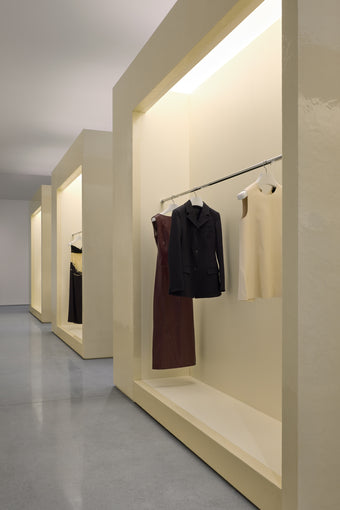 Interior of new Proenza Schouler flagship store at 153 Mercer Street. Image of large resin cubes with railings installed to display dark red leather dress, black blazer, and cream leather top