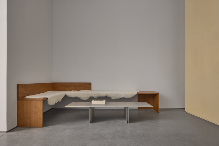 Interior of new Proenza Schouler flagship store at 153 Mercer Street. Image of cherrywood benches covered in cream fur fabric with a geometric silver table displaying magazines on top.