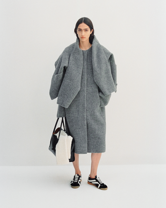 4x5 full body image of model Sara Caballero wearing the Albers Coat and Darcy Jacket, as well as holding the Tate Bag and wearing the Track Sneaker