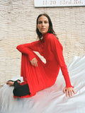 Image of model seated on covered car wearing Paula Dress in Sheer Crepe Jersey in red