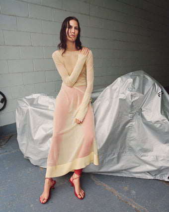 Image of model leaning against covered car, wearing Anneliese Dress in Organza Knit in resin over red tights