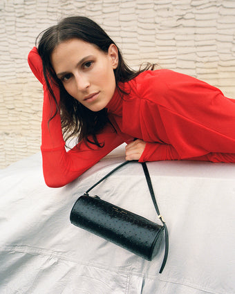 Cropped image of model wearing Paula Dress in red, carrying Silo Bag in Embossed Ostrich in black