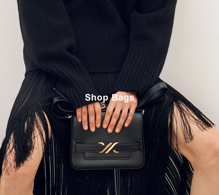 Cropped image of model wearing Everly Dress in Viscose Fringe Knit in black, carrying Monogram Box Bag in black, 'Shop Bags' overlaid