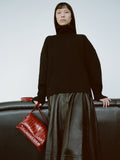 Cropped image of a model wearing Sandra Turtleneck in Eco Doubleface Cashmere in black, Moore Skirt in Glossy Leather in black, carrying a City Bag in Eel in rosewood.