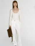 Cropped image of a model wearing Boyd Henley in Silk Viscose in ivory and Rory Pant in Crinkle Cotton Poplin in white, carrying City Bag in black.