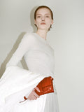 Cropped image of model wearing Roger Layered Top in Gauzy Jersey in Pale Grey and Margo Skirt in Gauzy Jersey in Pale Grey, carrying Flip Shoulder Bag in Eel in rosewood.