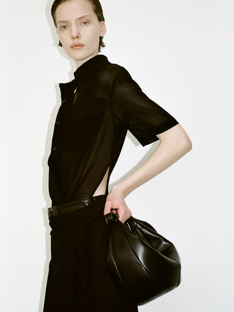 Cropped image of a model wearing Emory Dress in Mesh in black, carrying a Slide Bag in black.