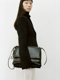 Cropped image of a model holding City Messenger Bag in black.