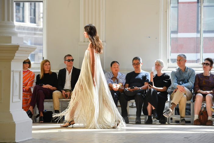 Wide image of model Loli Bahia walking the SS25 Proenza Schouler fashion show in a white fringe gown